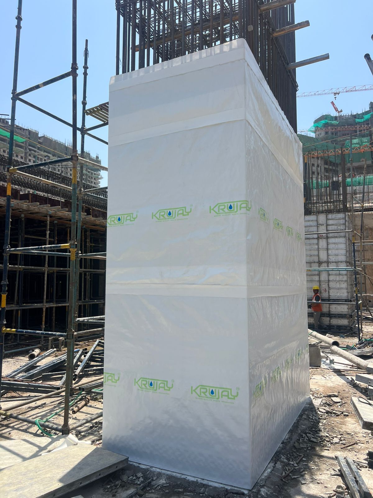 An RCC column wrapped in KRUJAY's white curing membrane at a live construction site in Ahmedabad